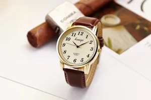 Close-up of vintage quartz watch with brown leather strap and classic beige dial face