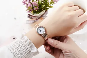 Detail shot of a rose gold chain bracelet watch with blue hands on a female wrist
