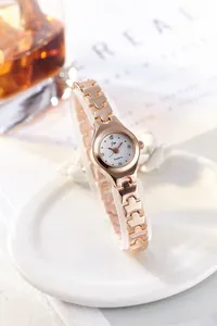 Detail of rose gold geometric hollow bracelet watch with rhinestone markers on white dial