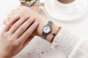 Close-up of elegant women's watch with steel mesh band and clover bracelet set