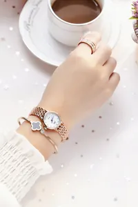 Close-up of rose gold watch set with clover bracelet and diamond ring on female wrist