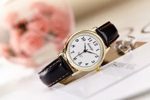 Close-up of retro quartz watch with white dial, black leather strap and orange stitching