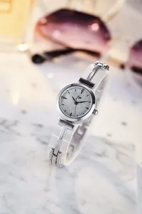 Close-up of silver metal watch dial with glitter finish and elegant chain strap on marble