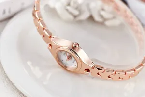 Macro shot of rose gold quartz watch with white dial and interlocking metal strap links