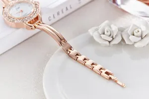 Detail of rose gold fashion watch featuring a crystal bezel and elegant metal link strap