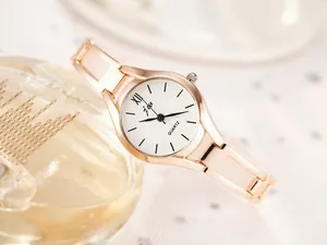 Detail of rose gold ladies' watch featuring a white dial with Roman numeral and metal strap