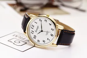 Detailed close-up of retro quartz watch with gold case, white dial, and black leather strap