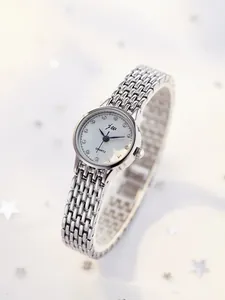 Close-up of elegant silver link bracelet watch with crystal markers on pearl white dial