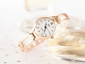 Detail showing rose gold mesh chain strap and white dial of a lady's quartz watch
