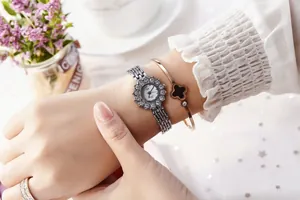 Detail of luxury rhinestone sunflower watch paired with a minimalist clover bracelet