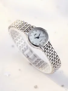 Close-up of silver mesh strap watch with quartz movement and crystal hour markers