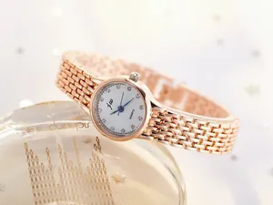 Detail of rose gold fashion watch with white rhinestone dial and blue needles