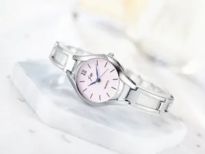 Detailed macro view of pink watch dial with silver hollow chain strap on marble surface