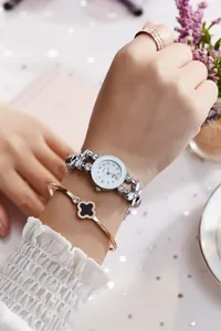 Gros plan d'une montre en strass argentés avec un bracelet trèfle en or rose élégant