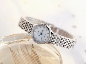 Close-up of stylish women's watch with mesh steel band and diamond-encrusted white dial