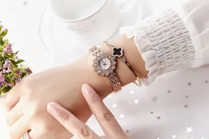 Detail of rose gold sunflower dial watch and clover bracelet on a female wrist