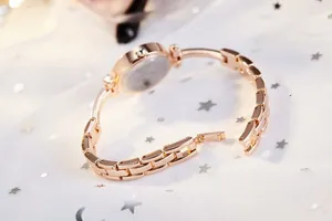 Detail view of rose gold women's bracelet watch with link strap and folding clasp on white mesh