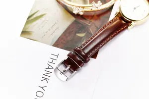 Macro shot of brown leather watch band and gold floral bracelet jewelry gift set