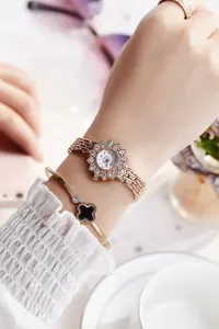 Close-up of rose gold watch with rhinestone bezel and black clover bracelet on wrist