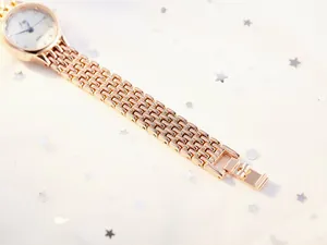 Detailed side view of rose gold stainless steel link watch strap and white dial
