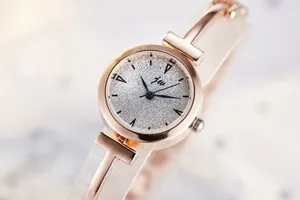 Detail of rose gold bangle watch with glitter silver dial and polished metal strap