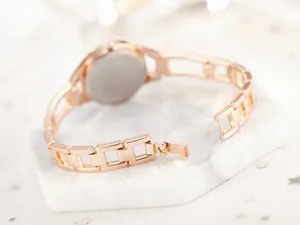 Macro shot of rose gold metal link strap and folding clasp detail on a lady watch