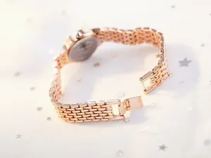 Detailed macro shot of rose gold metal watch strap links with secure jewelry clasp