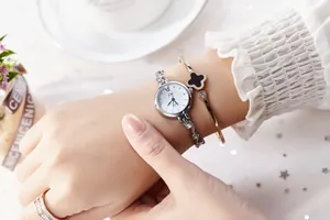 Gros plan d'une montre à quartz argentée avec bracelet trèfle et bague scintillante