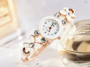 Vue détaillée d'une montre bracelet fleurie en or rose avec cristaux et cadran blanc