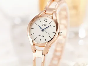 Detail of rose gold link bracelet watch featuring white dial and blue needles