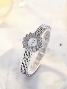 Close-up of luxury women's silver quartz watch with sparkling rhinestone sunflower case
