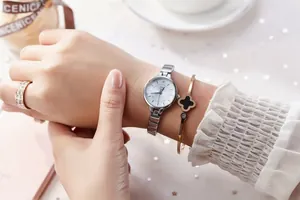 Close-up of stylish JW women's quartz watch with steel band and gold clover bracelet