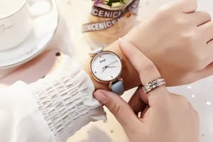 Gros plan d'une montre dorée avec bracelet bleu clair et bague sertie de cristaux