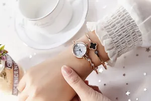 Montre à quartz or rose avec bracelet trèfle sur un décor de table vintage