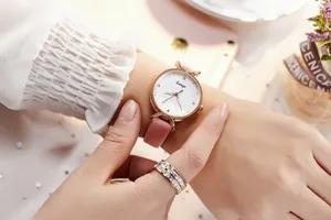 Détail d'une montre femme en or rose avec bracelet en cuir rose et bague en argent sertie