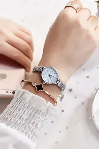 Silver quartz watch paired with a rose gold clover bangle on a woman's wrist