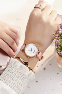 Détail d'une montre élégante pour femme en or rose avec bracelet cuir rose et trèfle