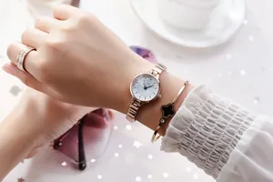 Elegant rose gold watch paired with a black clover bracelet and luxury accessories
