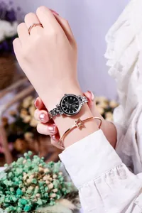 Close-up of stylish silver watch with black dial paired with star bracelet and V-ring