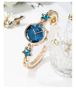 Close-up of rose gold watch with blue star crystal charms and sunburst dial detail