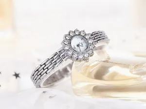 Macro detail of silver fashion watch with rhinestone flower bezel and quartz dial