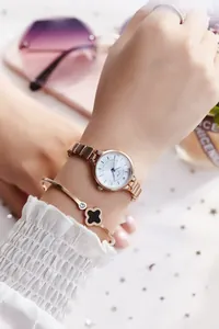 Detail of JW rose gold quartz watch and black clover bracelet on woman's wrist