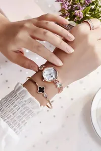 Close-up of rose gold watch and bracelet set featuring a black clover bangle on a wrist