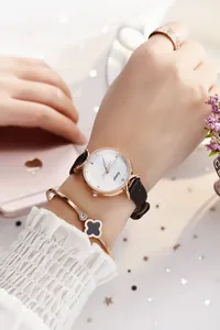 Détail d'une montre femme élégante avec bracelet en cuir, jonc trèfle et bague