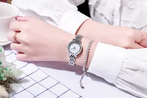 Detail einer silbernen Damenuhr und eines glitzernden Strass-Armbands am Handgelenk