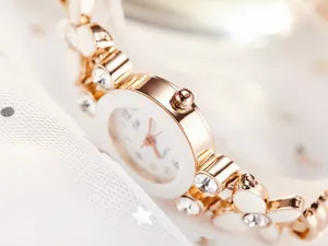 Gros plan montre or rose avec bracelet fleurs en émail blanc et strass brillants