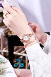 Nahaufnahme von roségoldener Damenuhr und funkelndem Armband-Set mit Strasssteinen