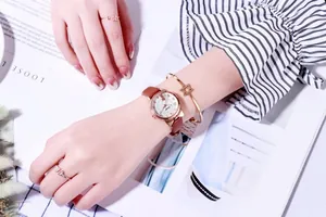 Quarzuhr-Detail mit roségoldenem Katzenohr-Gehäuse und braunem Lederarmband mit Schmuck