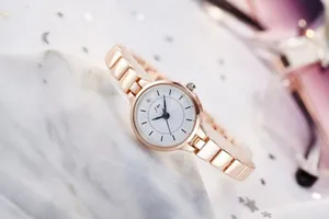 Detailed close-up of rose gold watch dial with white face and minimalist hour markers