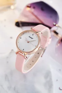 Gros plan sur le bracelet en cuir rose et boîtier doré rose sur fond marbre